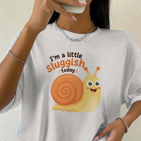 Person wearing a white t-shirt with a cartoon snail and text on a plain background