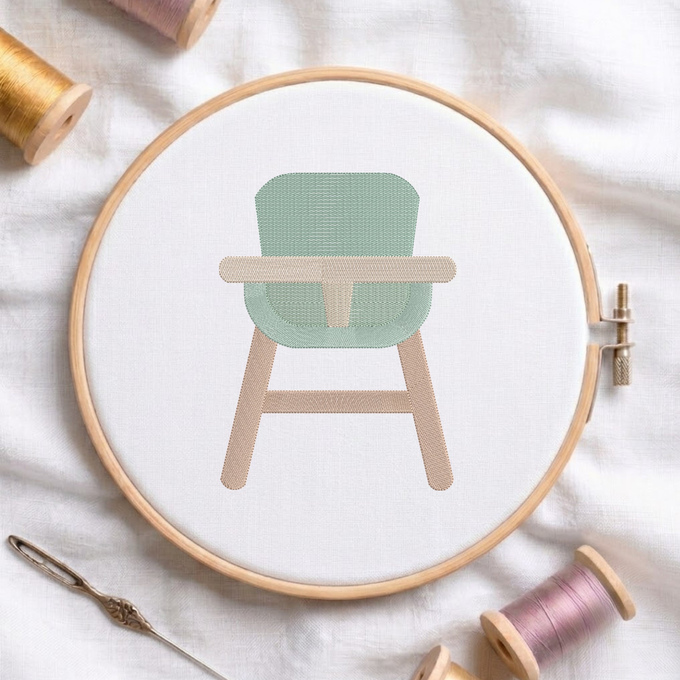 An embroidered baby high chair design with a green seat and beige wooden legs, stitched inside a wooden hoop on white fabric with sewing threads.