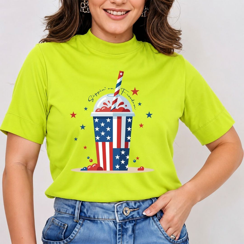 A smiling woman wearing a bright lime green mock-neck t-shirt featuring a large patriotic slushie cup design printed on the front.
