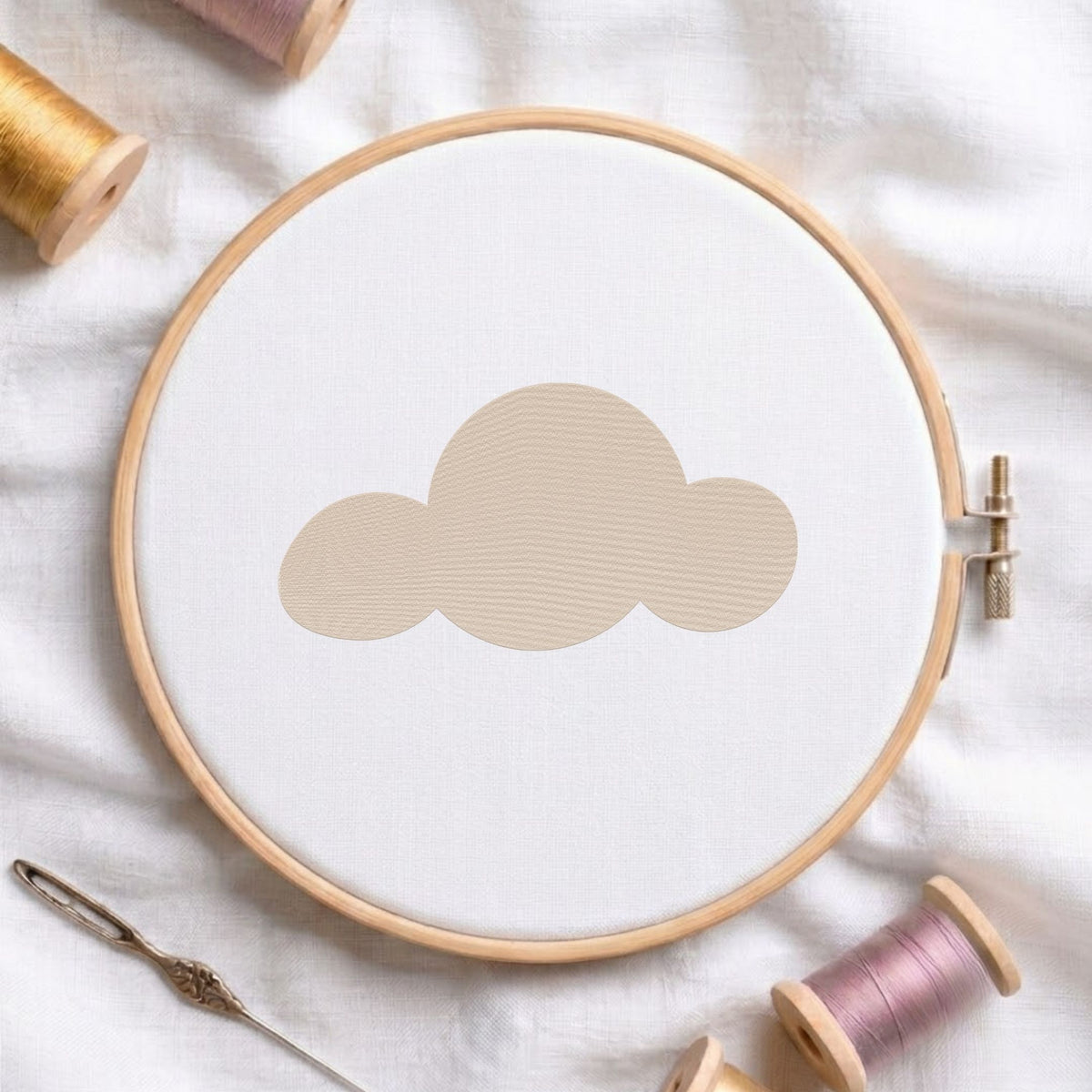 Minimalist cute cloud machine embroidery design shown in a wooden embroidery hoop on white fabric with thread spools and a needle   