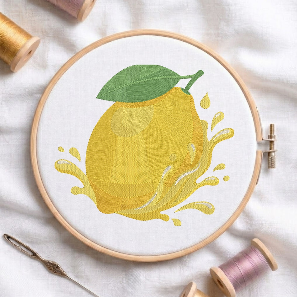 The lemon embroidery design centered in a wooden embroidery hoop, displayed with embroidery thread spools and a needle on a white fabric background.