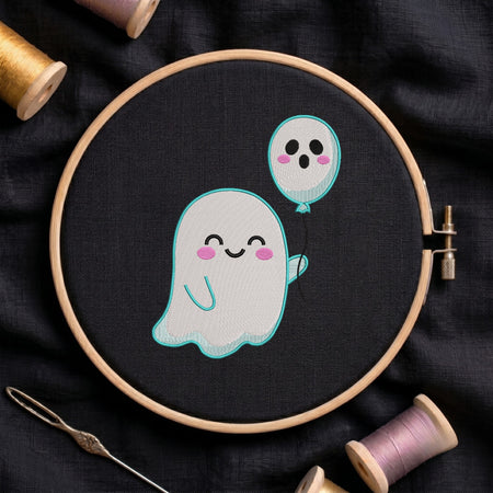 A circular embroidery hoop holding black fabric with a cute embroidered design of a smiling white ghost holding a light blue balloon. The hoop is styled on a dark fabric background with spools of thread and a needle.
