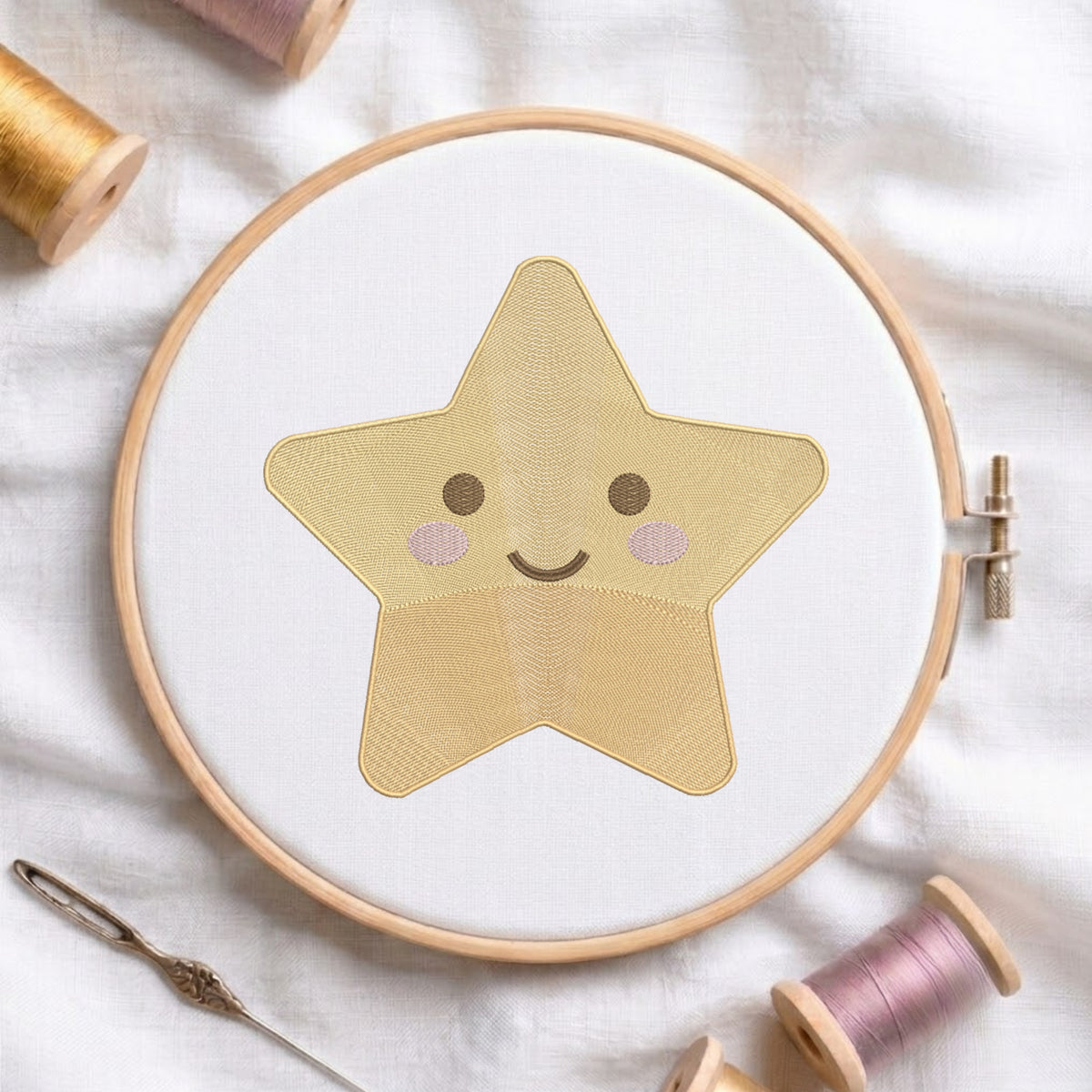 A star-shaped embroidered patch with a smiling face, stitched in a light wood hoop on white fabric, surrounded by spools of thread and a needle on a white textured background.