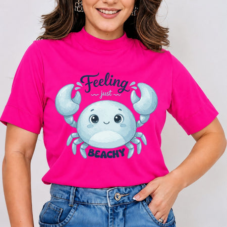 A person wearing a bright hot-pink t-shirt featuring a blue cartoon crab graphic and the text "Feeling just BEACHY".