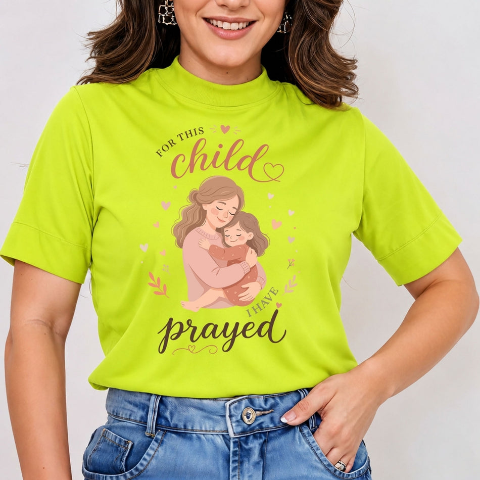 A close-up of a person wearing a bright lime-green t-shirt featuring a mother-and-child illustration and the text "For this child I have prayed."