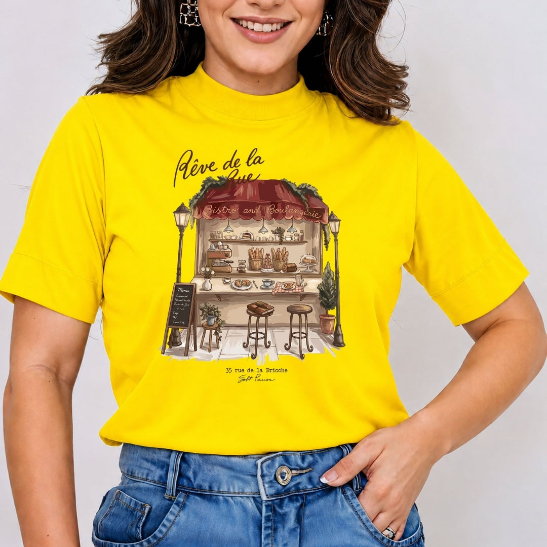 Smiling person wearing a bright yellow t-shirt featuring the charming French bakery stall graphic and typography.