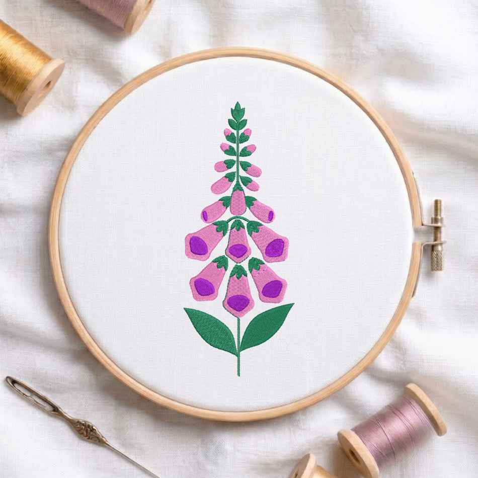 Pink and purple foxglove bell flower with green stem embroidered inside a round wooden hoop with thread spools.