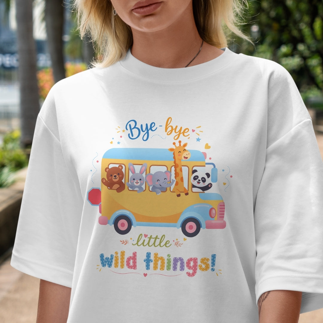 Person wearing a white t-shirt with a colorful graphic of a bus and animals, with text 'Bye bye little wild things!'.