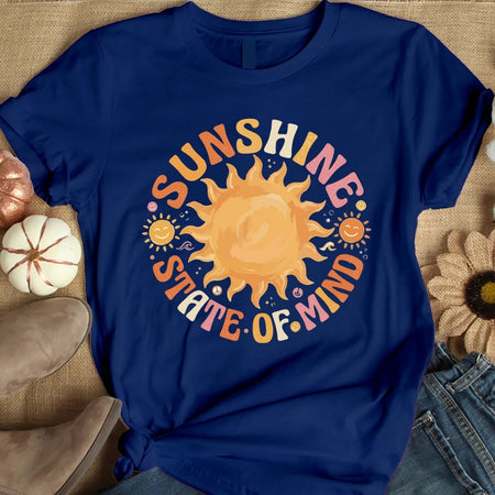 Blue t-shirt with a sun graphic and 'Sunshine State of Mind' text on a textured surface.