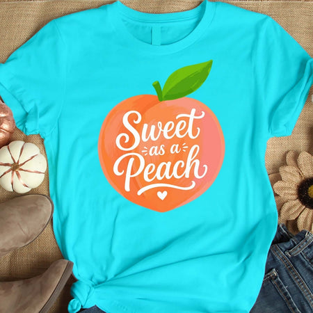 Turquoise t-shirt with 'Sweet as a Peach' graphic on a textured surface