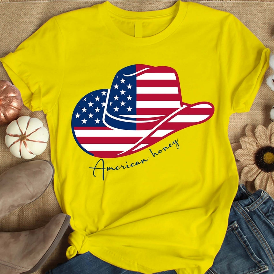 Yellow t-shirt with American flag design and 'American honey' text on a textured surface.