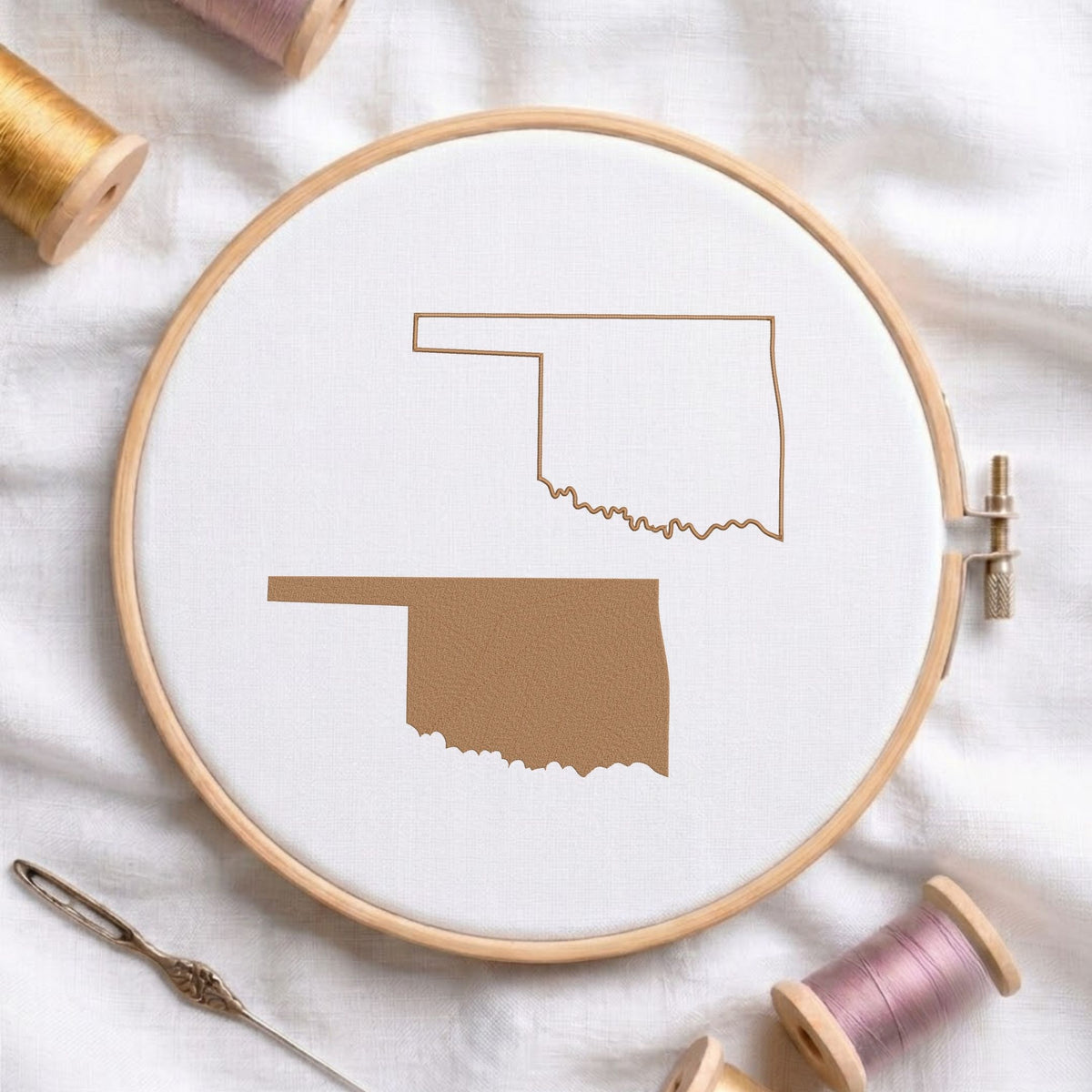Oklahoma state map fill and outline machine embroidery design, displayed in a wooden hoop on white fabric with thread spools and a needle