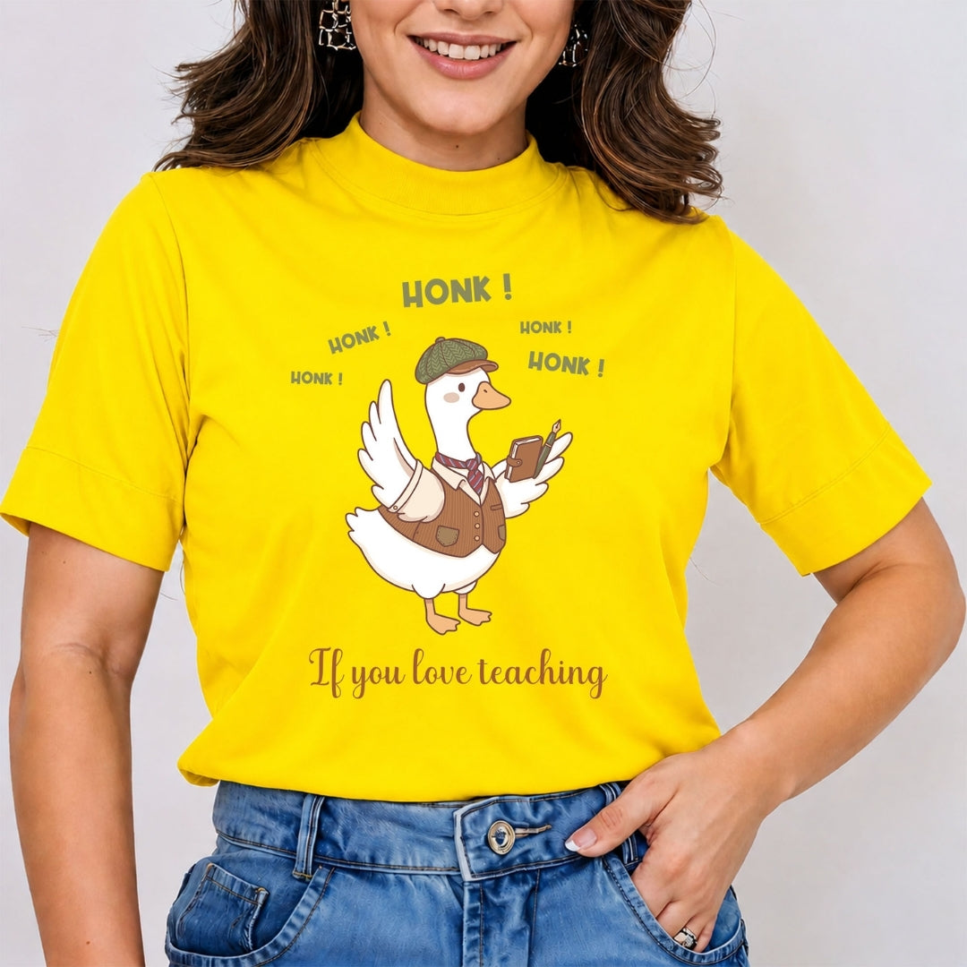 Smiling person wearing a bright yellow t-shirt featuring a funny illustrated duck dressed in a tweed cap and vest, holding a book and pen, surrounded by the text "HONK! HONK! HONK! HONK! If you love teaching".