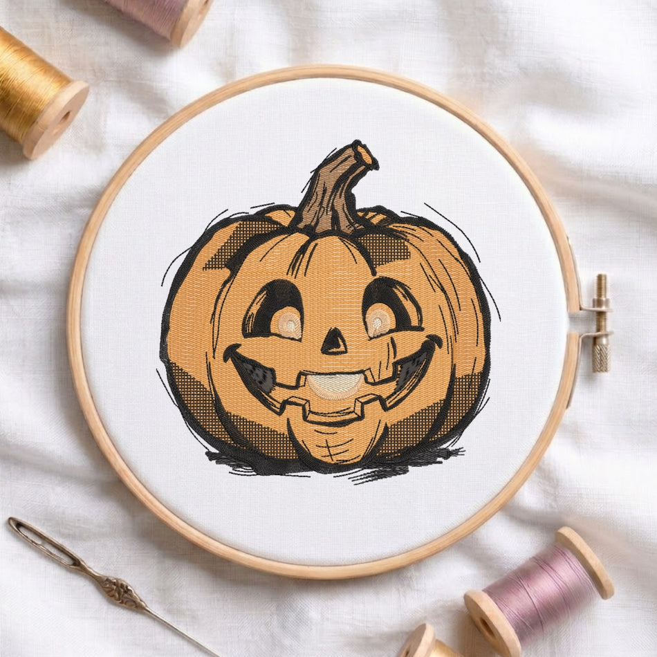 A circular embroidery hoop holding white fabric with a printed or stitched jack-o'-lantern pumpkin design in orange, black, and brown. The hoop is photographed on a white fabric surface with spools of thread and a needle around it.