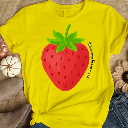 Yellow t-shirt with a strawberry graphic and text on a textured surface