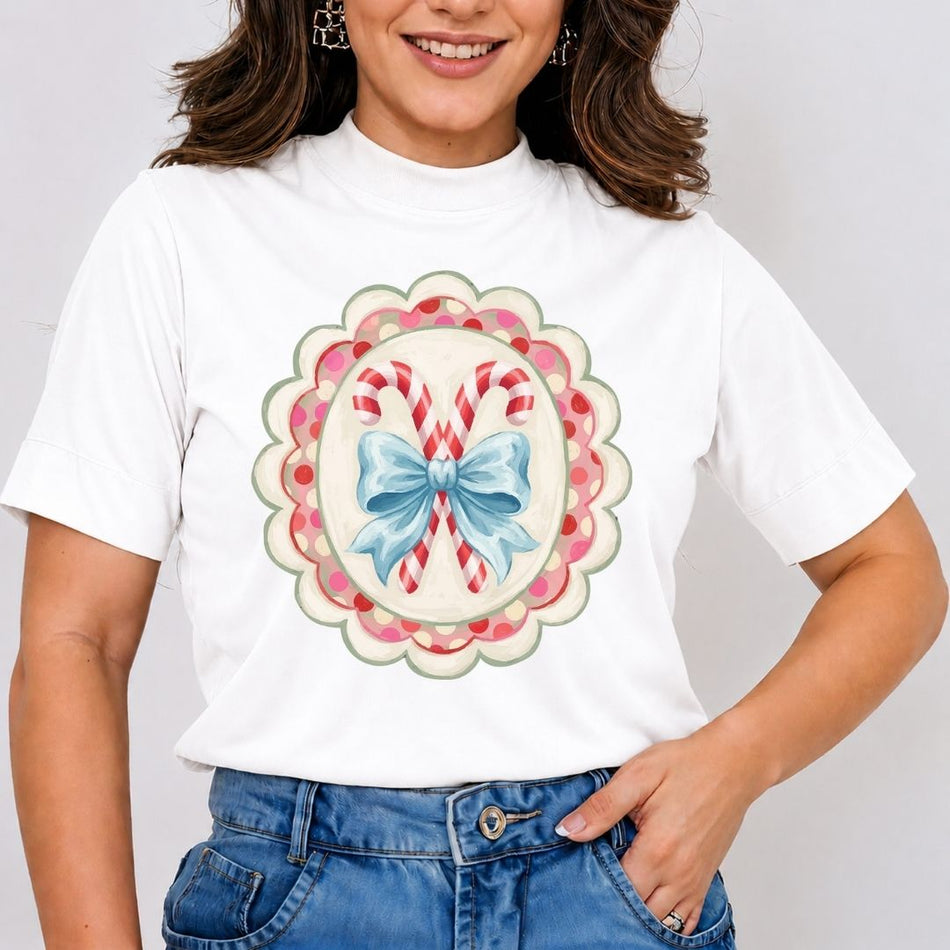 A woman wearing a white short-sleeve t-shirt with a colorful Christmas-themed graphic print featuring candy canes and a blue bow, paired with blue jeans.