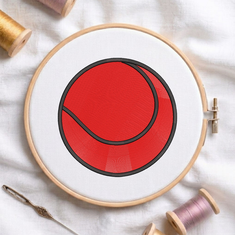 A circular embroidery hoop holding white fabric with a red and black tennis ball design, surrounded by spools of thread and a needle on a white fabric background.