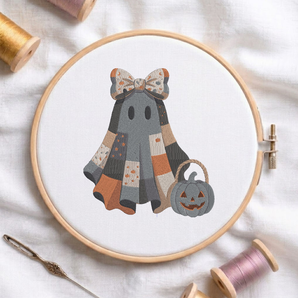 Cute patchwork Halloween ghost holding a jack-o-lantern bucket with a patterned bow machine embroidery design displayed inside a round wooden hoop on white linen fabric.
