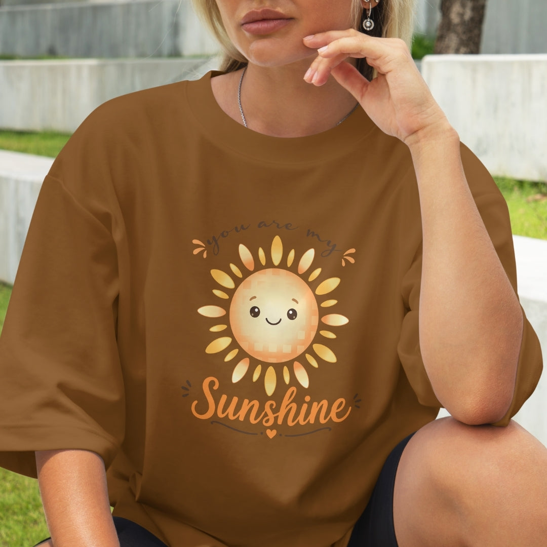 Person wearing a brown t-shirt with a sun graphic and 'Sunshine' text.