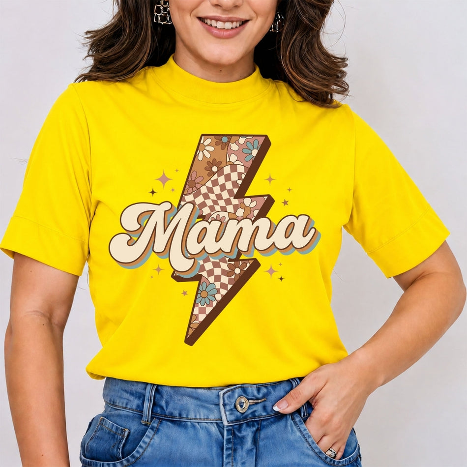 A woman wearing a bright yellow short-sleeve t-shirt with a retro lightning bolt graphic that says 'Mama' in cream script, paired with blue jeans against a light gray background.
