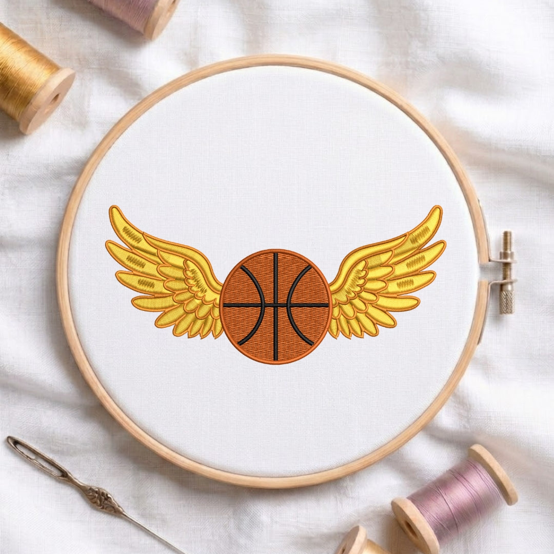 Embroidery hoop with a basketball design featuring wings on a white fabric background.