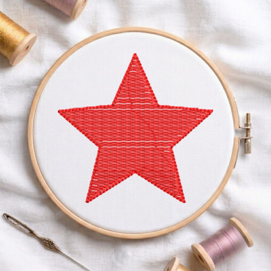 The "Be Kind" embroidery design centered in a wooden embroidery hoop, surrounded by embroidery thread spools and a needle.