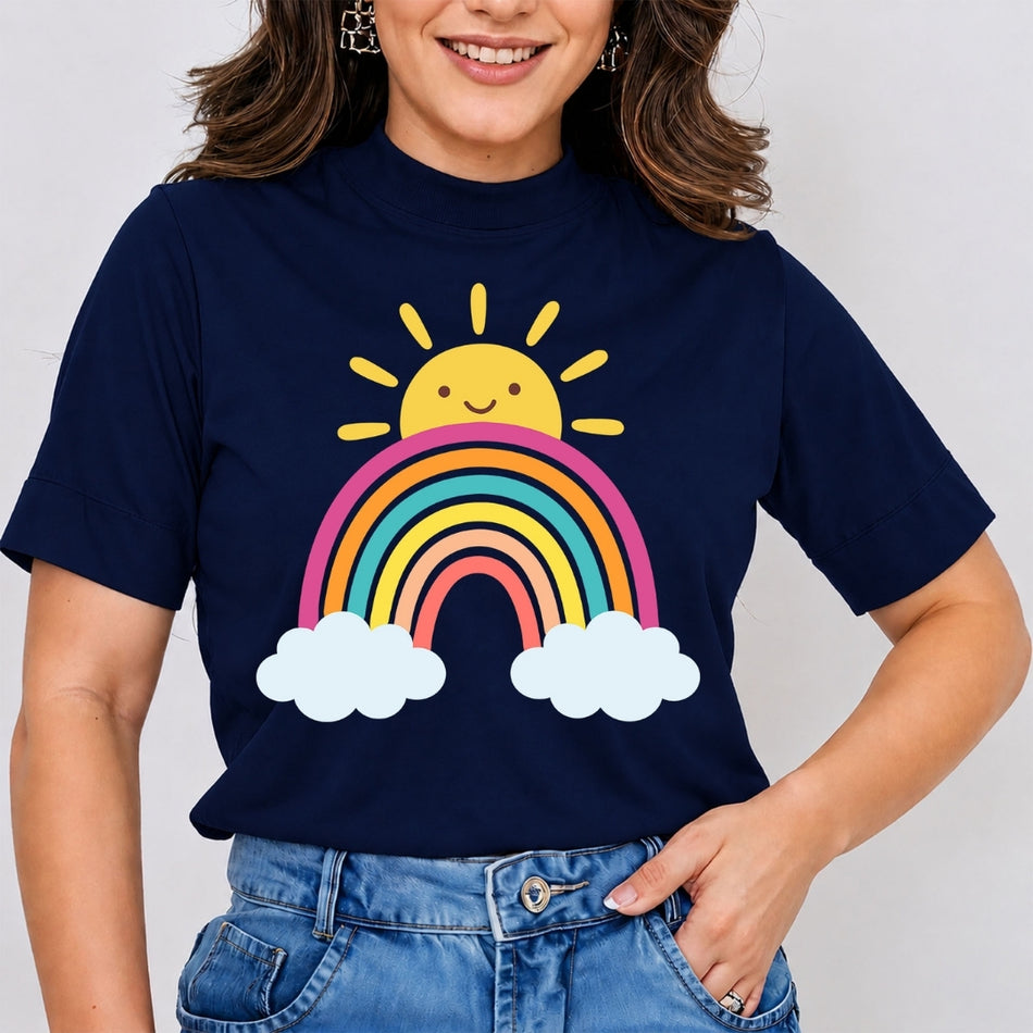 A woman wearing a navy blue t-shirt with a colorful cartoon sun and rainbow graphic, paired with blue jeans, against a light gray background.