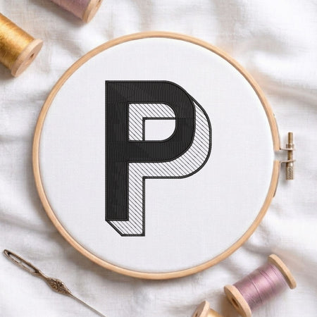 An embroidered 3D block letter "P" with striped shading texture, stitched inside a wooden hoop on white fabric with sewing threads.