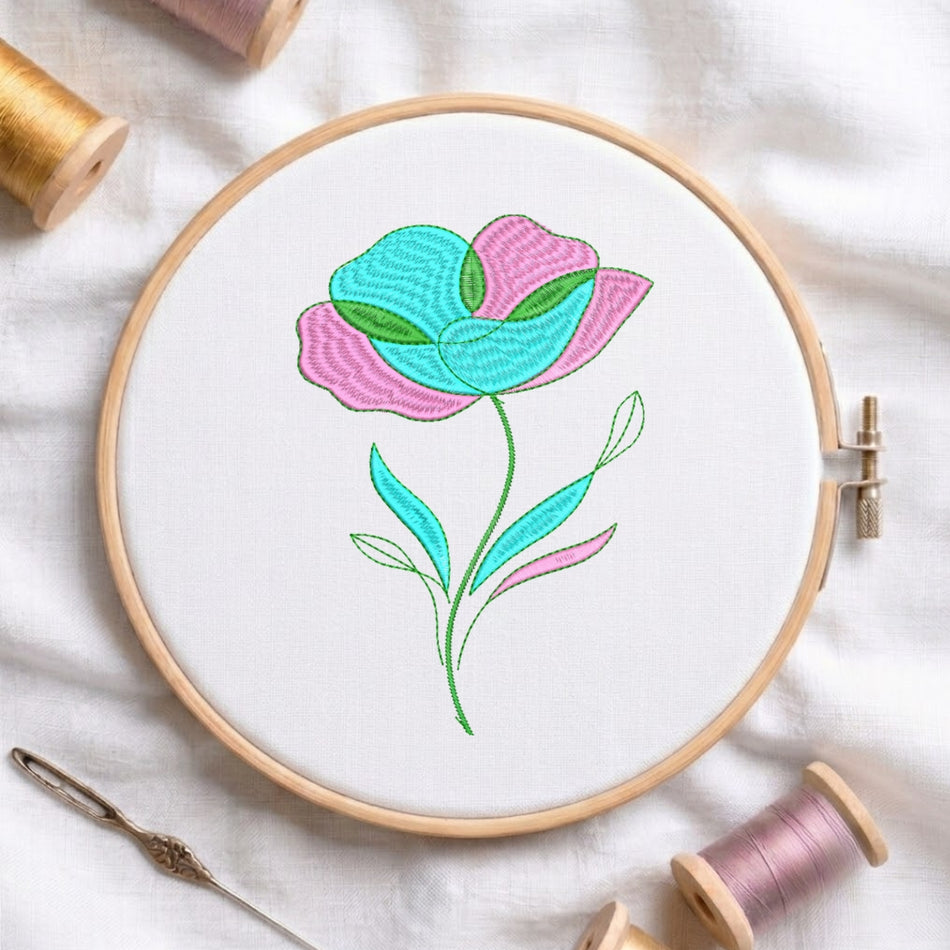 A floral embroidery design in a wooden hoop, featuring pink and turquoise petals with green leaves on a white fabric background, surrounded by spools of thread and a needle.