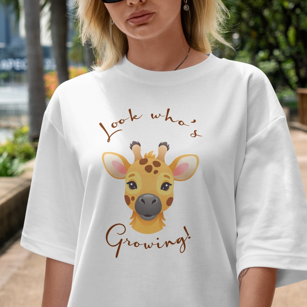 Person wearing a white t-shirt with a giraffe graphic and text outdoors.