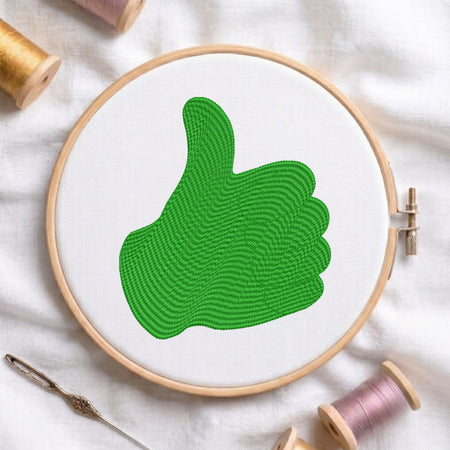 Embroidery hoop with green thumb up design on a white fabric background