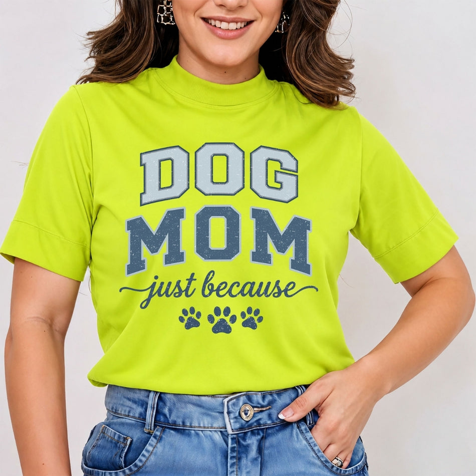 Woman wearing a lime green mock neck t-shirt featuring a blue and white vintage-style "Dog Mom just because" graphic print with paw prints, tucked into blue jeans.