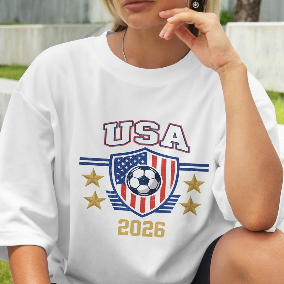 Person wearing a white t-shirt with 'USA 2026' soccer design.