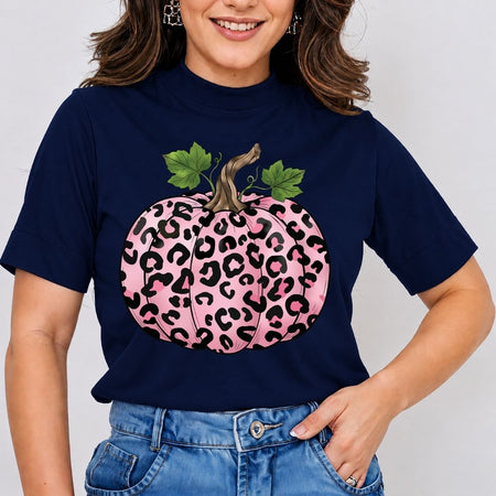 Person wearing a navy blue t-shirt with a pink leopard print pumpkin design on a plain background