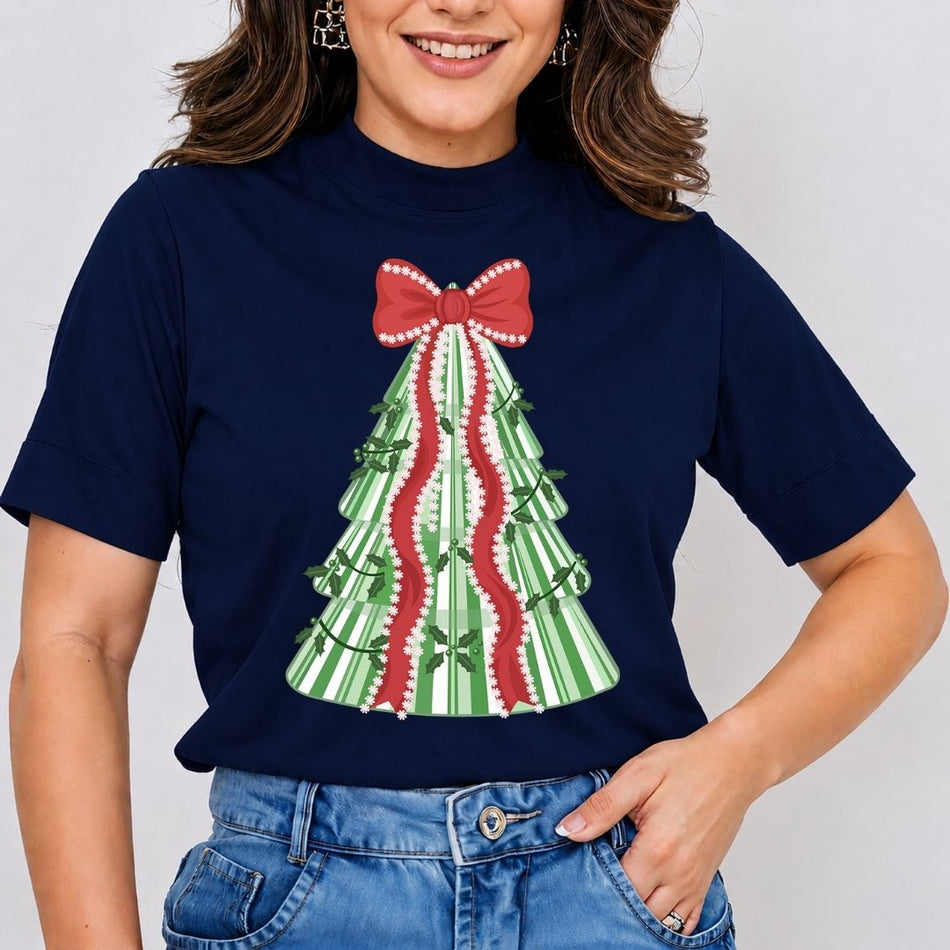 A woman wearing a navy blue short-sleeve t-shirt with a Christmas tree graphic made of green and white stripes, a red bow, and red wavy ribbons, paired with blue jeans.