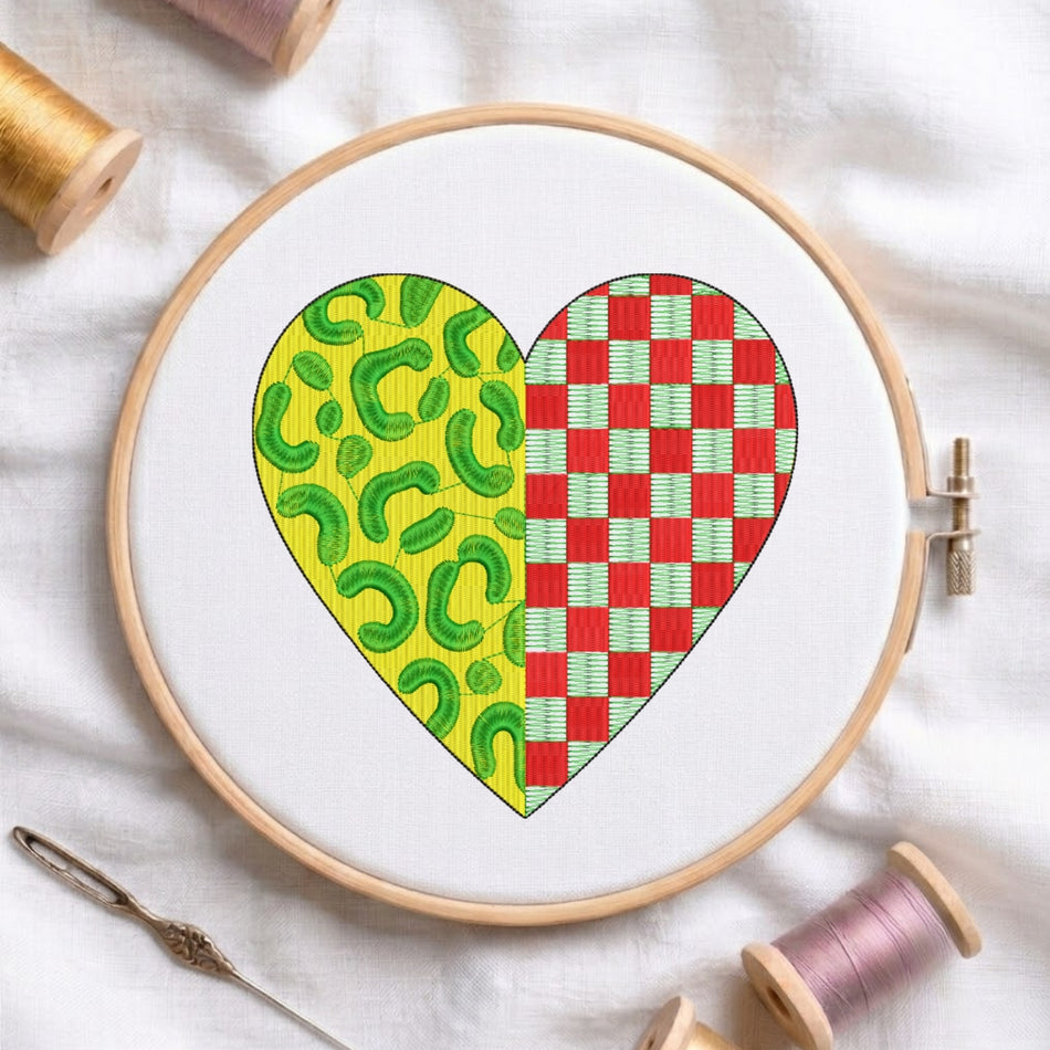 A split heart embroidery pattern with leopard and red checkered textures displayed inside a wooden embroidery hoop on white fabric.