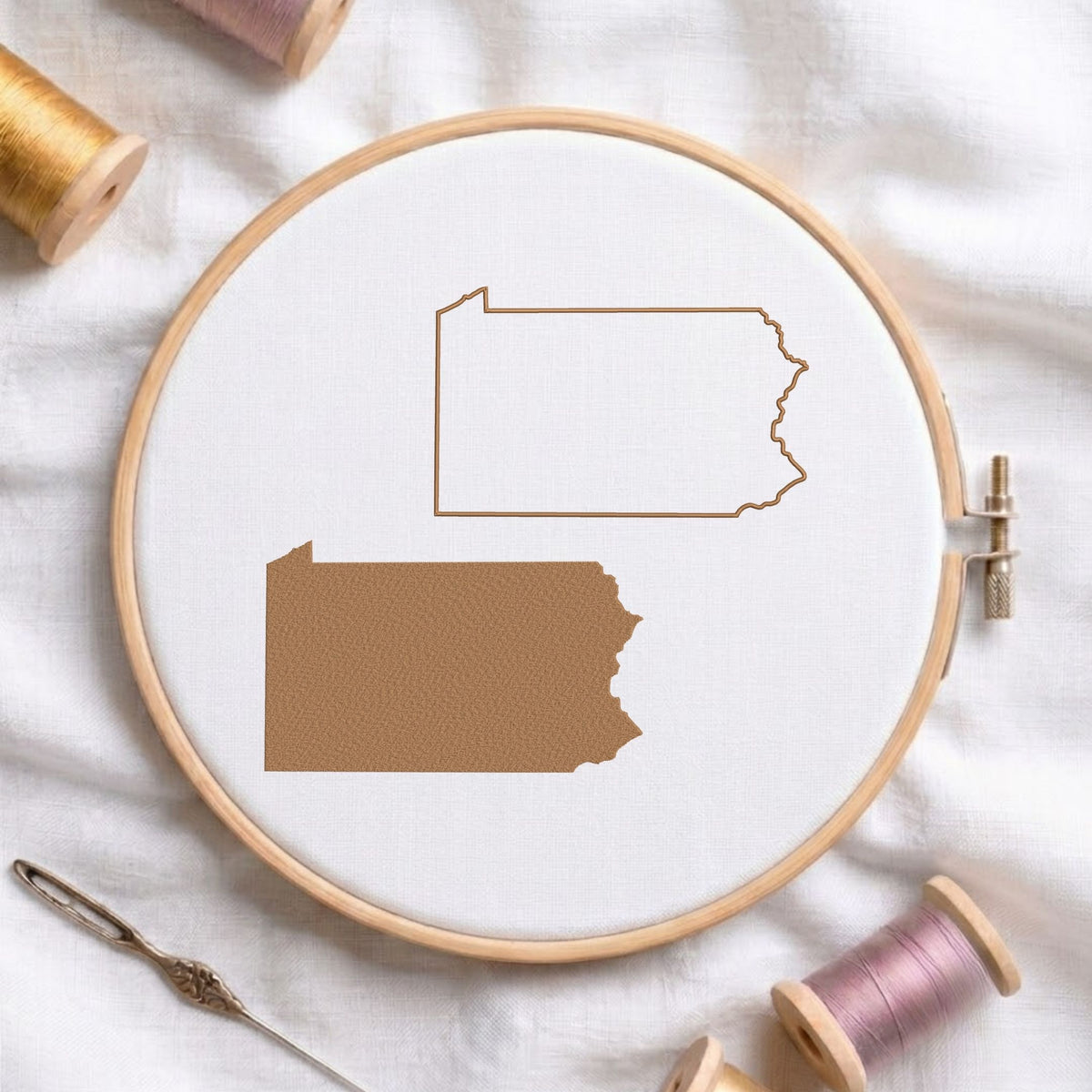  Oregon state map fill and outline machine embroidery design, displayed in a wooden hoop on white fabric with thread spools and a needle.   
