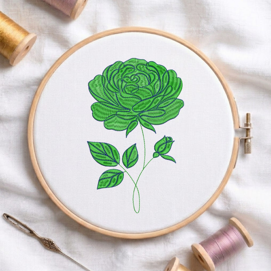A circular embroidery hoop holding white fabric with a green rose design stitched in the center, surrounded by spools of thread and a needle on a white fabric background.