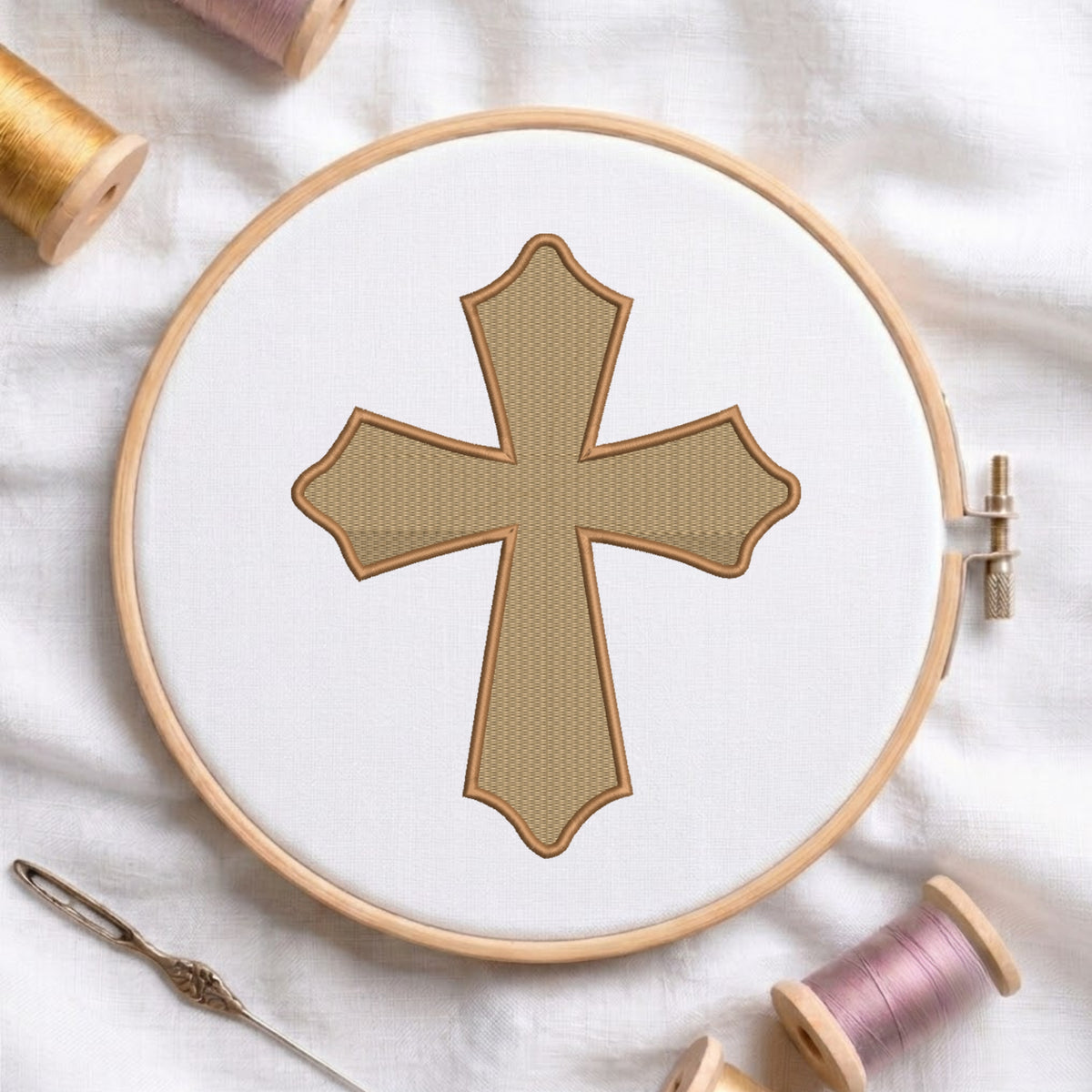 Tan and dark brown scalloped cross embroidered on white fabric inside a wooden hoop.