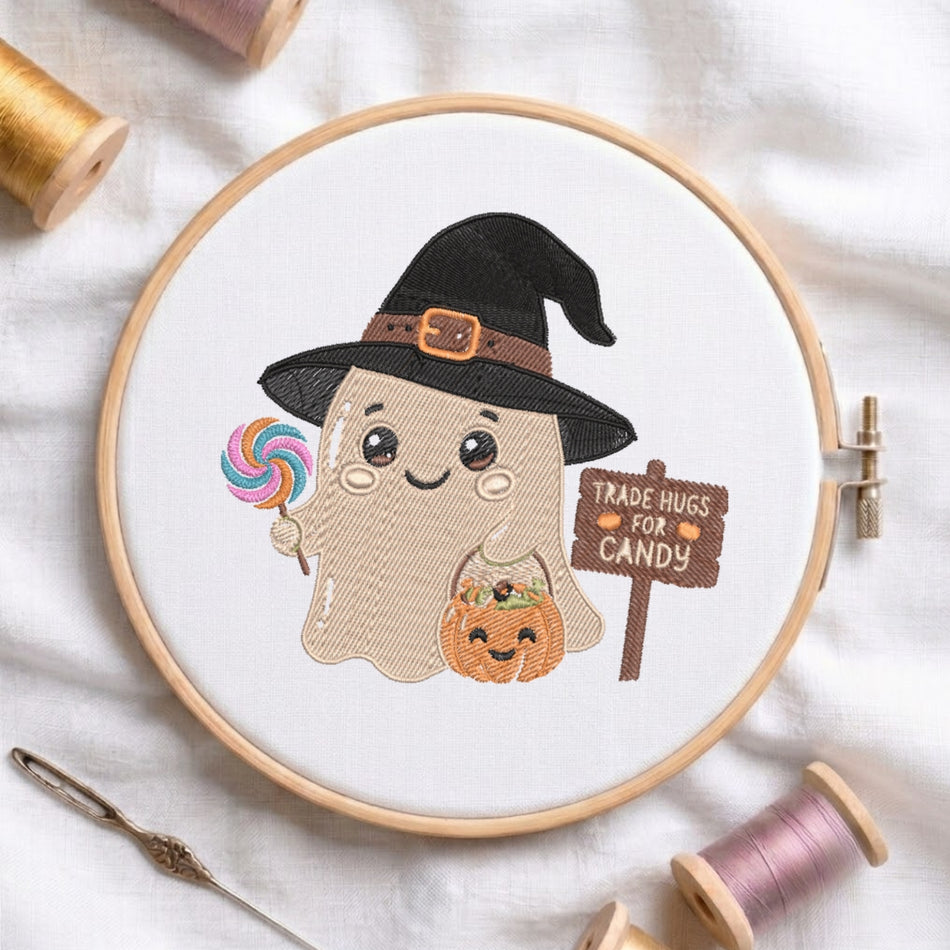 A circular embroidery hoop displays a cute cartoon ghost design with a black witch hat, holding a rainbow lollipop and a small jack-o'-lantern, next to a sign that reads 'TRADE HUGS FOR CANDY'. The hoop is styled on a white fabric background with spools of thread and a needle.