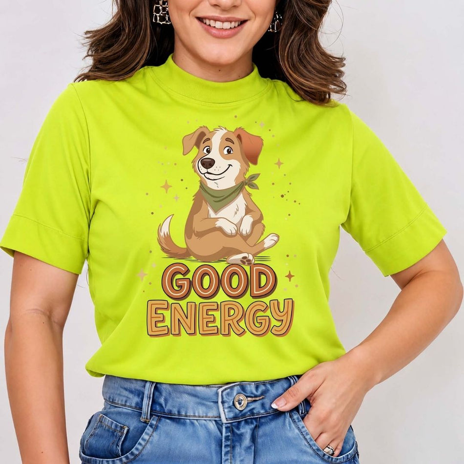 A woman wearing a bright lime green mock-neck t-shirt with a cartoon dog graphic and the words 'GOOD ENERGY' printed on the front, paired with blue jeans.