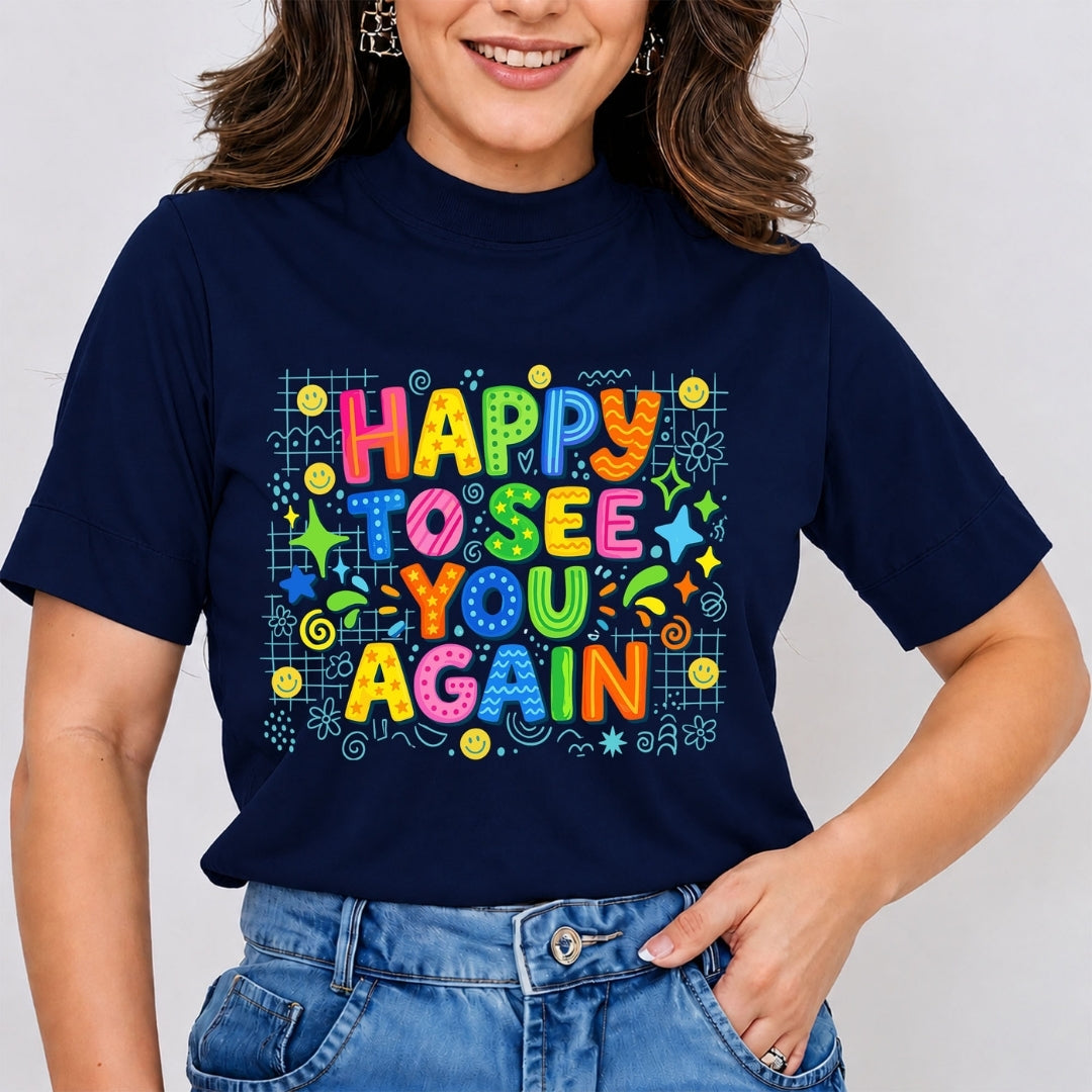 A woman wearing a navy blue t-shirt with a colorful retro graphic that reads 'HAPPY TO SEE YOU AGAIN' in multicolored bubble letters surrounded by doodles, paired with blue jeans.