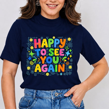 A woman wearing a navy blue t-shirt with a colorful retro graphic that reads 'HAPPY TO SEE YOU AGAIN' in multicolored bubble letters surrounded by doodles, paired with blue jeans.
