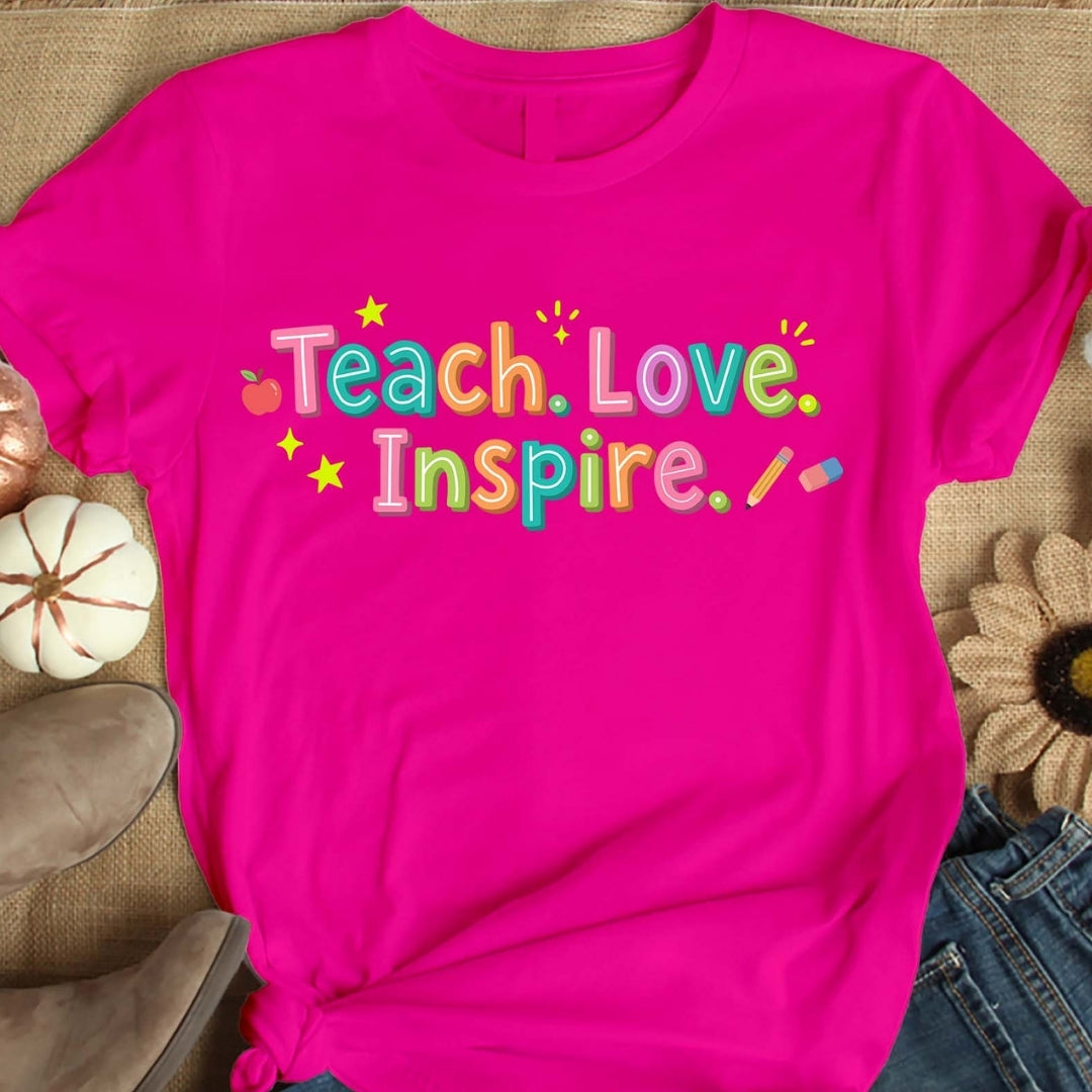 Pink t-shirt with 'Teach. Love. Inspire.' text on a textured surface