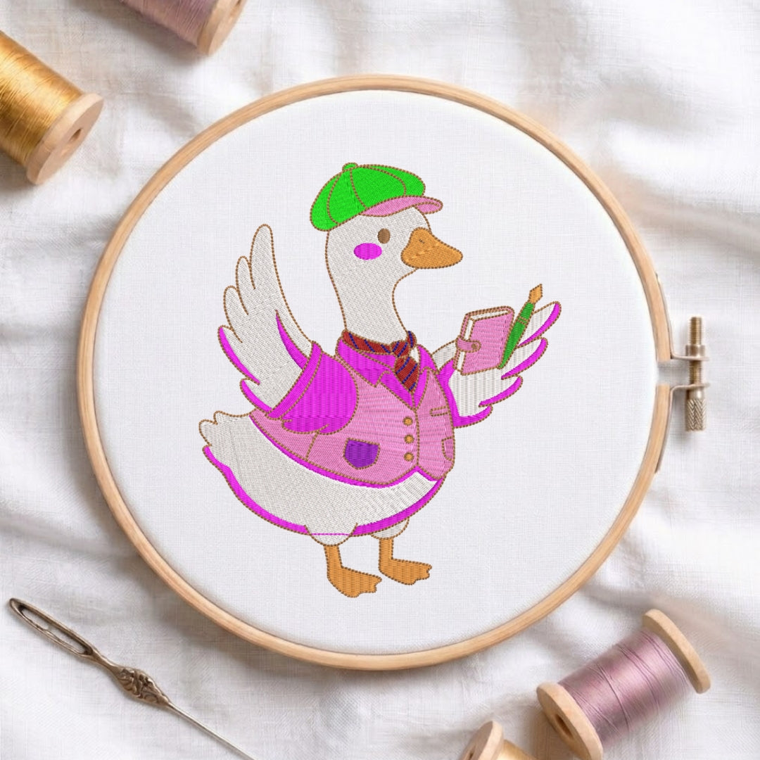 An embroidered design of a duck wearing a green cap, a pink vest, and holding a small notebook and pen, displayed inside a wooden embroidery hoop surrounded by sewing tools and thread.