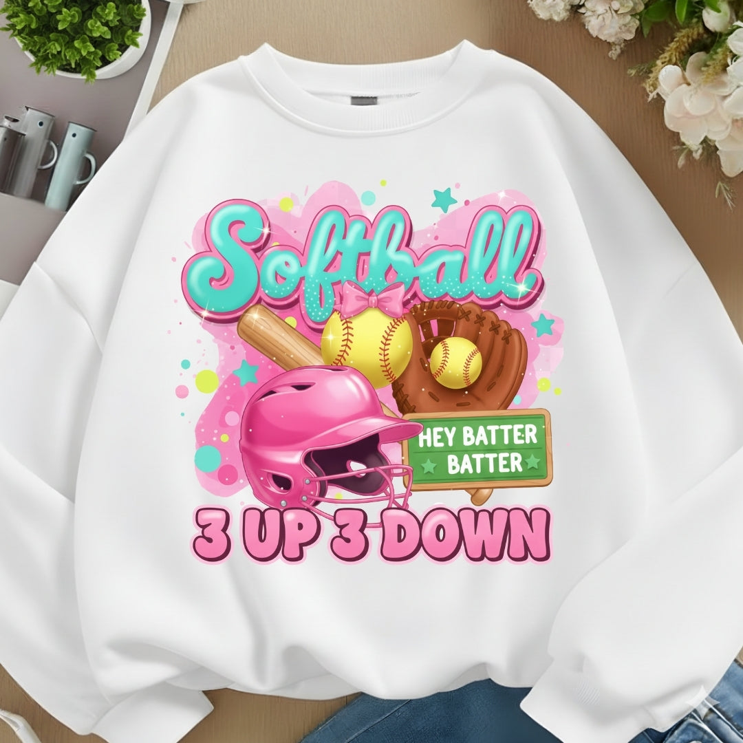 White sweatshirt with colorful softball-themed design on a wooden surface.