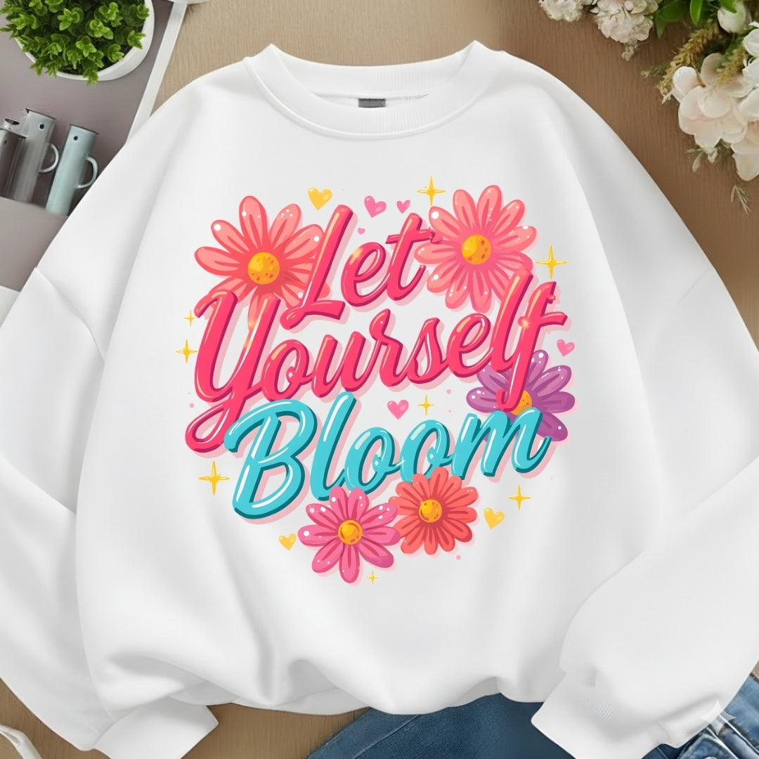 White sweatshirt with 'Let Yourself Bloom' text and flowers on a neutral background