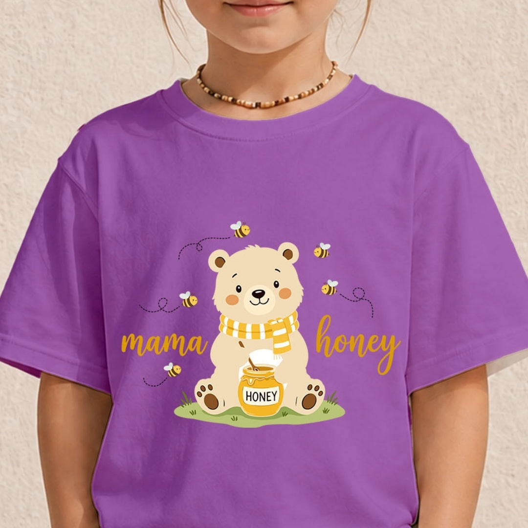 A child wearing a purple short-sleeve t-shirt with a cartoon graphic of a bear holding a jar of honey, surrounded by bees, with the words 'mama honey' in yellow script.