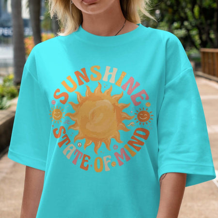 Person wearing a turquoise t-shirt with a sun graphic and 'Sunshine State of Mind' text.