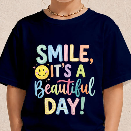 A person wearing a navy blue T-shirt with a colorful retro-style graphic that reads 'SMILE, IT'S A Beautiful DAY!' in pastel letters with a yellow smiley face and stars.